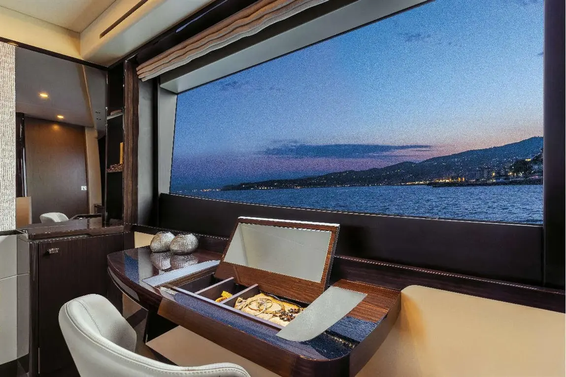 Luxury yacht interior with a view of the sea at dusk, featuring a stylish desk with a mirror and decorative accessories.